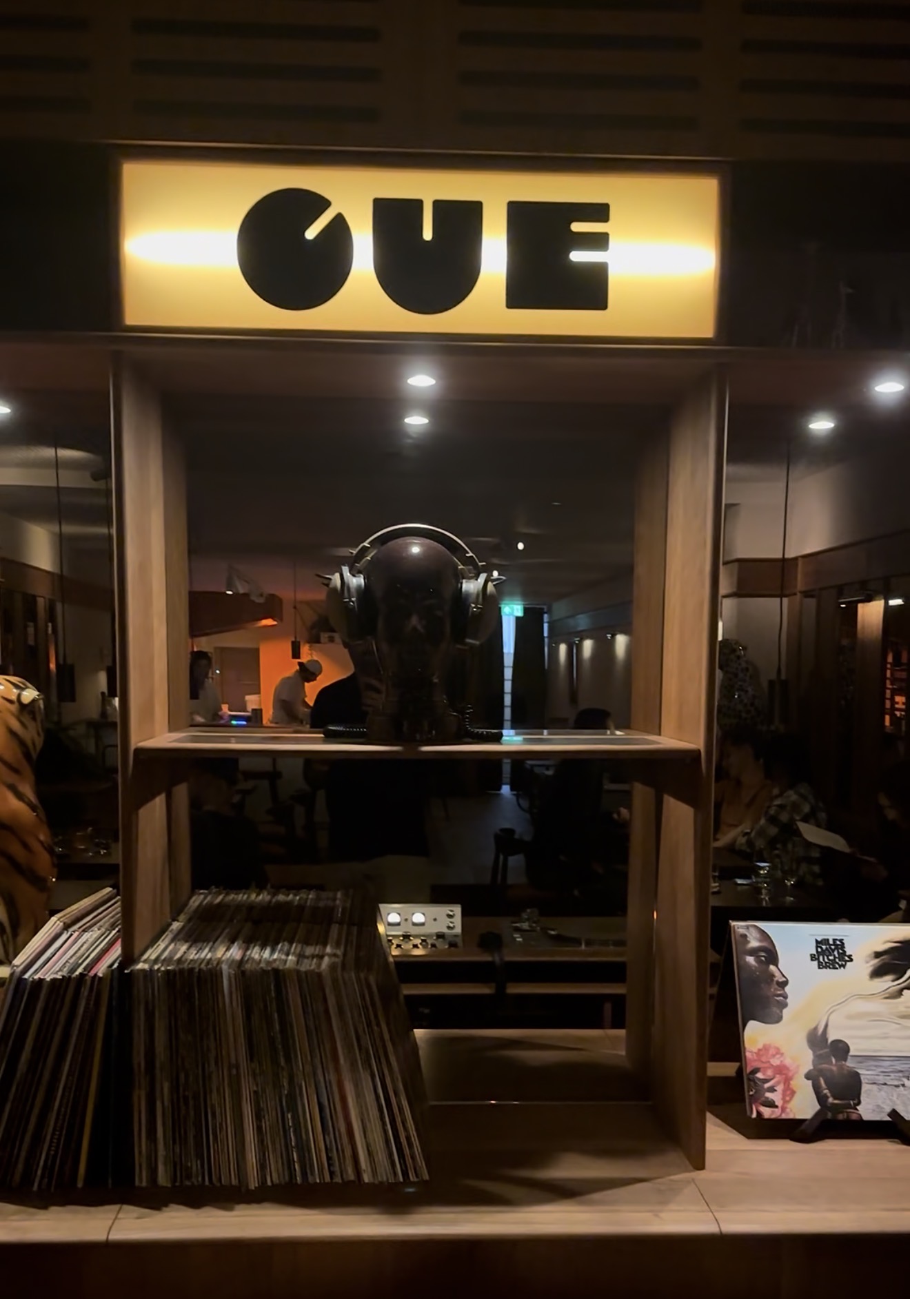 Records and headphones beneath the illuminated CUE sign.